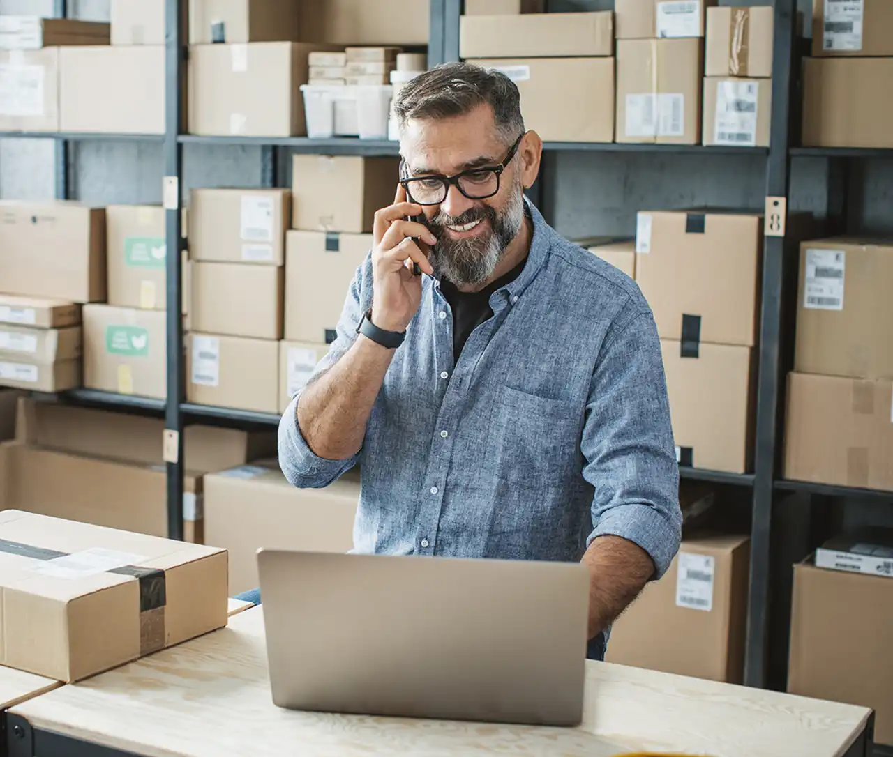 Mann im Lager mit Smartphone und Laptop