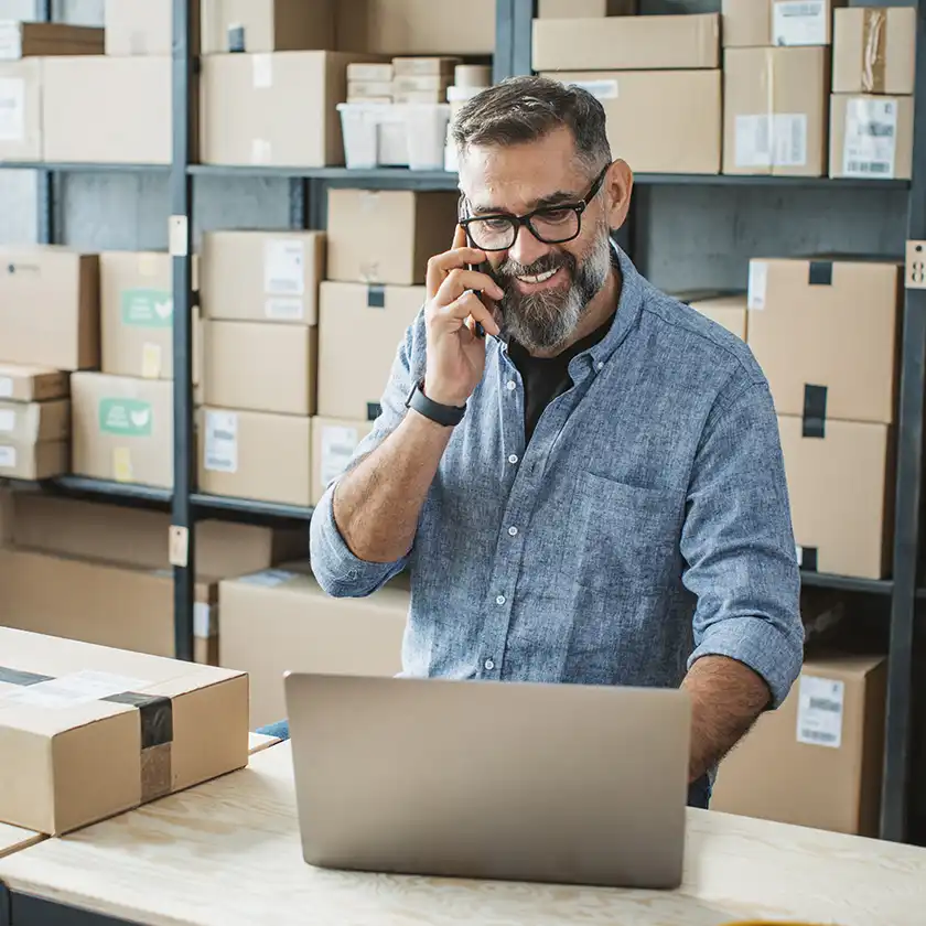 Man in the warehouse with smartphone and laptop