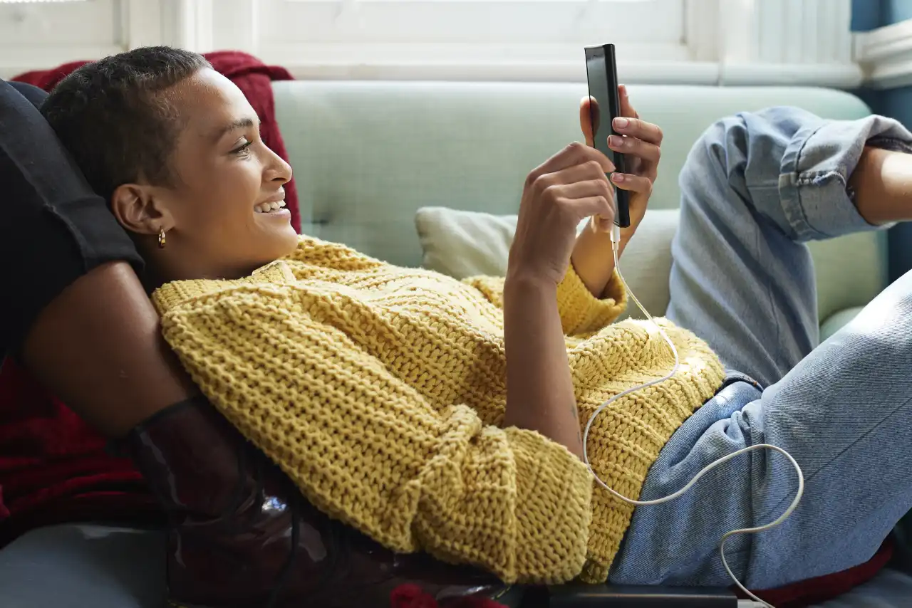 Woman on the sofa checks her savings accounts with her mobile phone