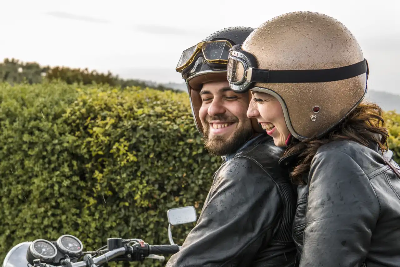 Un homme et une femme rient sur leur moto